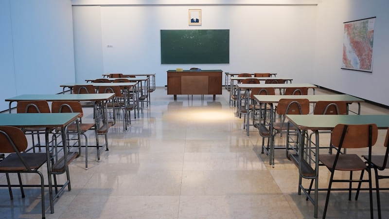 Étudiants en uniforme devant une école britannique typique en briques rouges pour illustrer le vocabulaire scolaire anglais